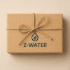 Prostokątne pudełko owinięte brązowym papierem z przewiązaną sznurkiem kokardą, na którym widoczny jest napis Z-WATER oraz logo w kształcie kropli z liściem w środku, na jasnobeżowym tle.